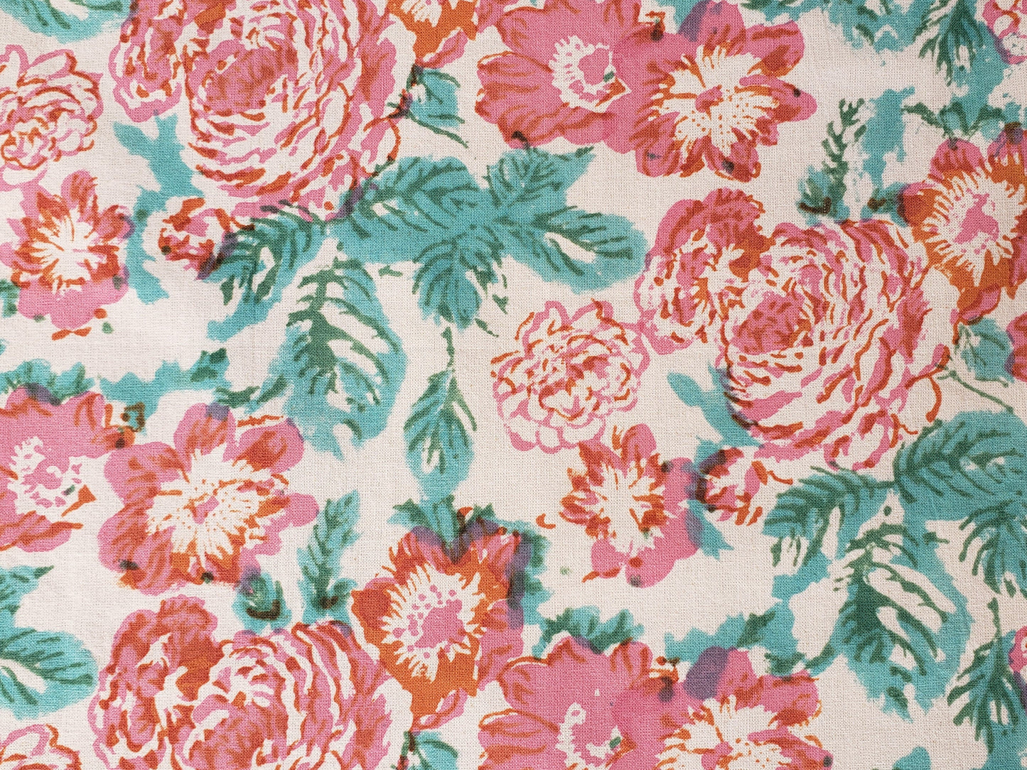Detalle de mantel cuadrado base blanca estampado a mano con flores rosas y naranjas con filos turquesa. Hecho en la India