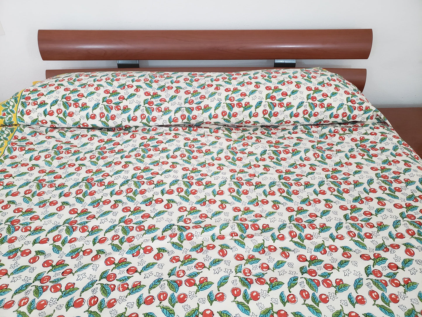 Detalle de sobrecama 100% algodón estampado a mano, base blanca con cerezas rojas y tallos verdes con borde amarillo. Hecho en la India.