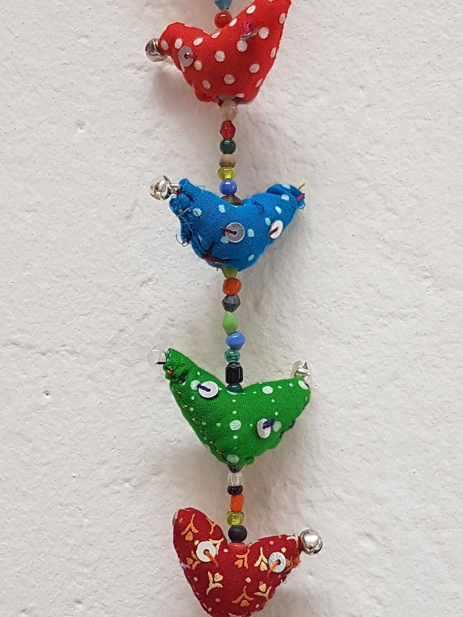 Colgante hindu con pajaritos de tela, separados por cuentas multicolor y campana al final.