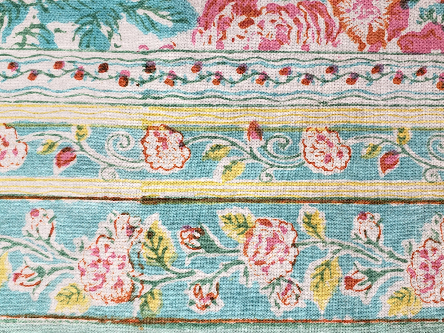 Borde de mantel cuadrado base blanca estampado a mano con flores rosas y naranjas con filos turquesa. Hecho en la India