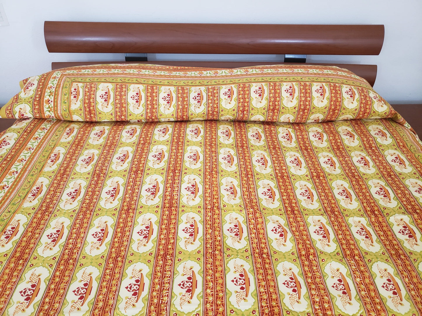 Detalle de sobrecama 100% algodón estampado a mano, base beige con diseño lineal en tonos verde, naranja y rojo. Hecho en la India.