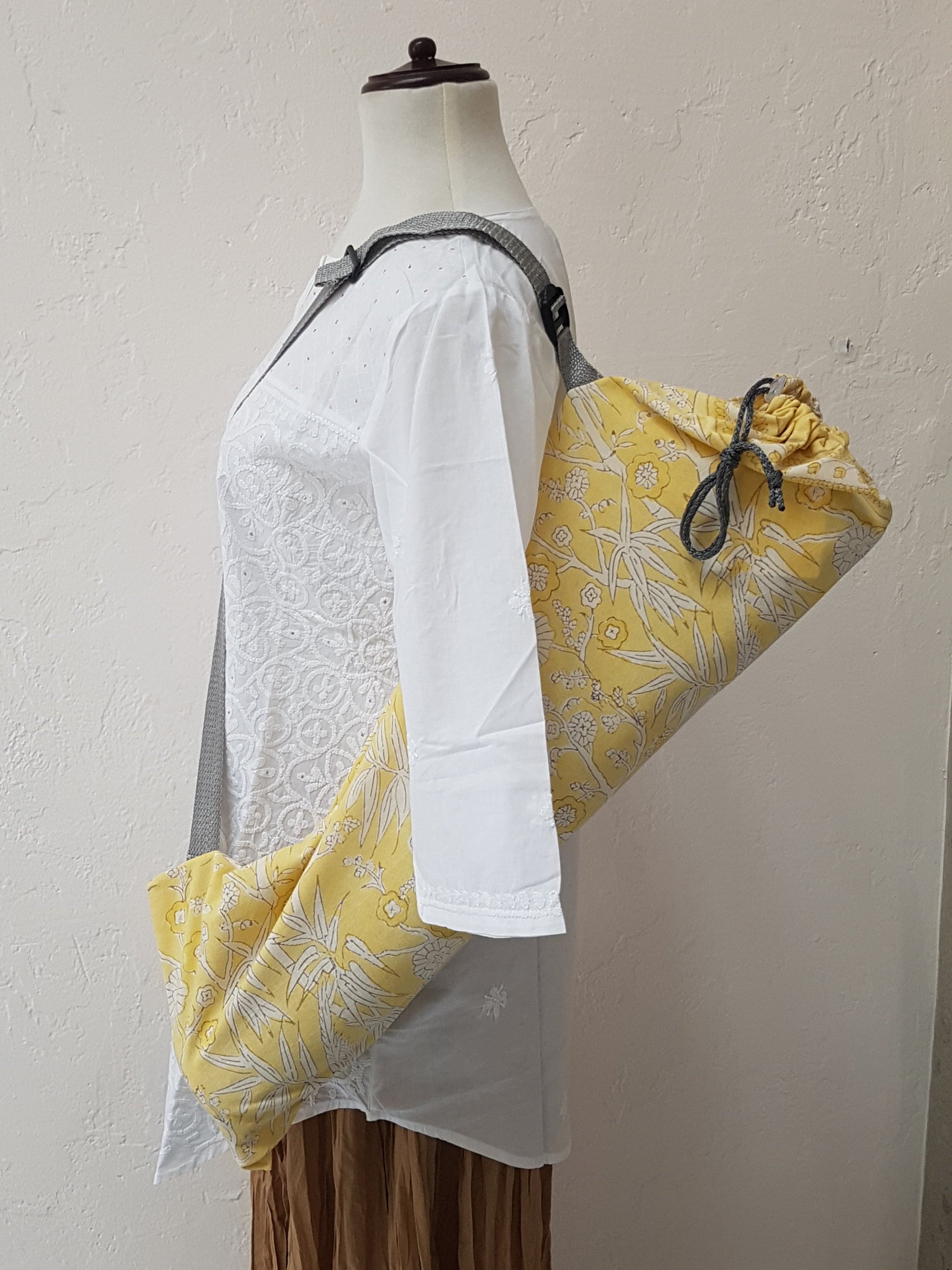 Vista frontal de funda para tapete de yoga 100% algodón, estampada a mano amarilla vegetación y pájaros en color gris con blanco. Hecha en la India.