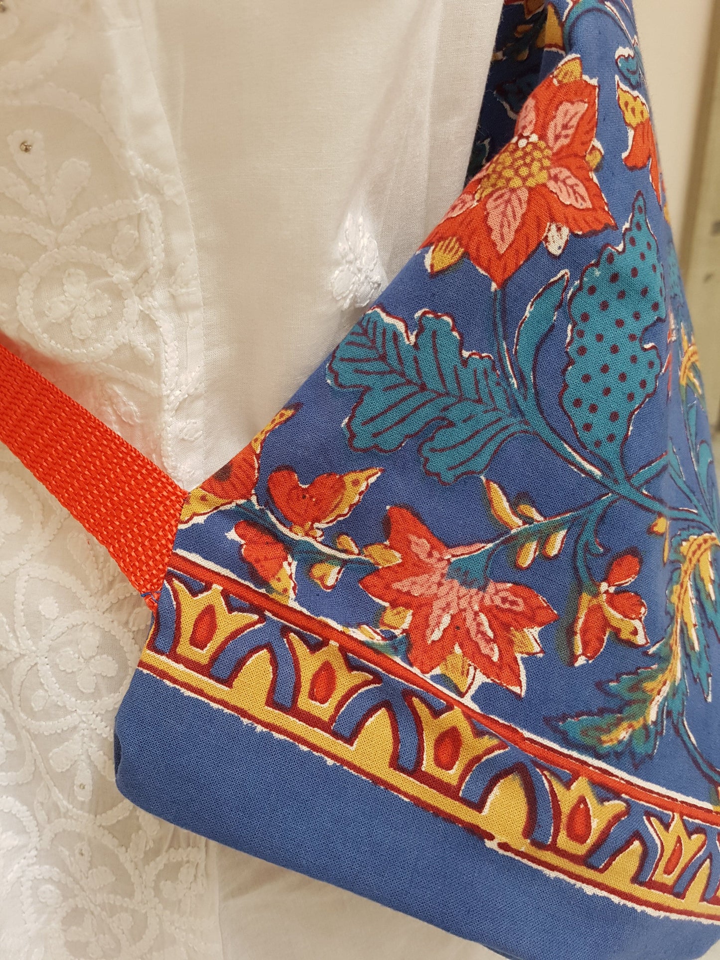 Detalle de correa roja en funda para tapete de yoga 100% algodón, estampada azul flores rojas y detalles beige. Hecha en la India.