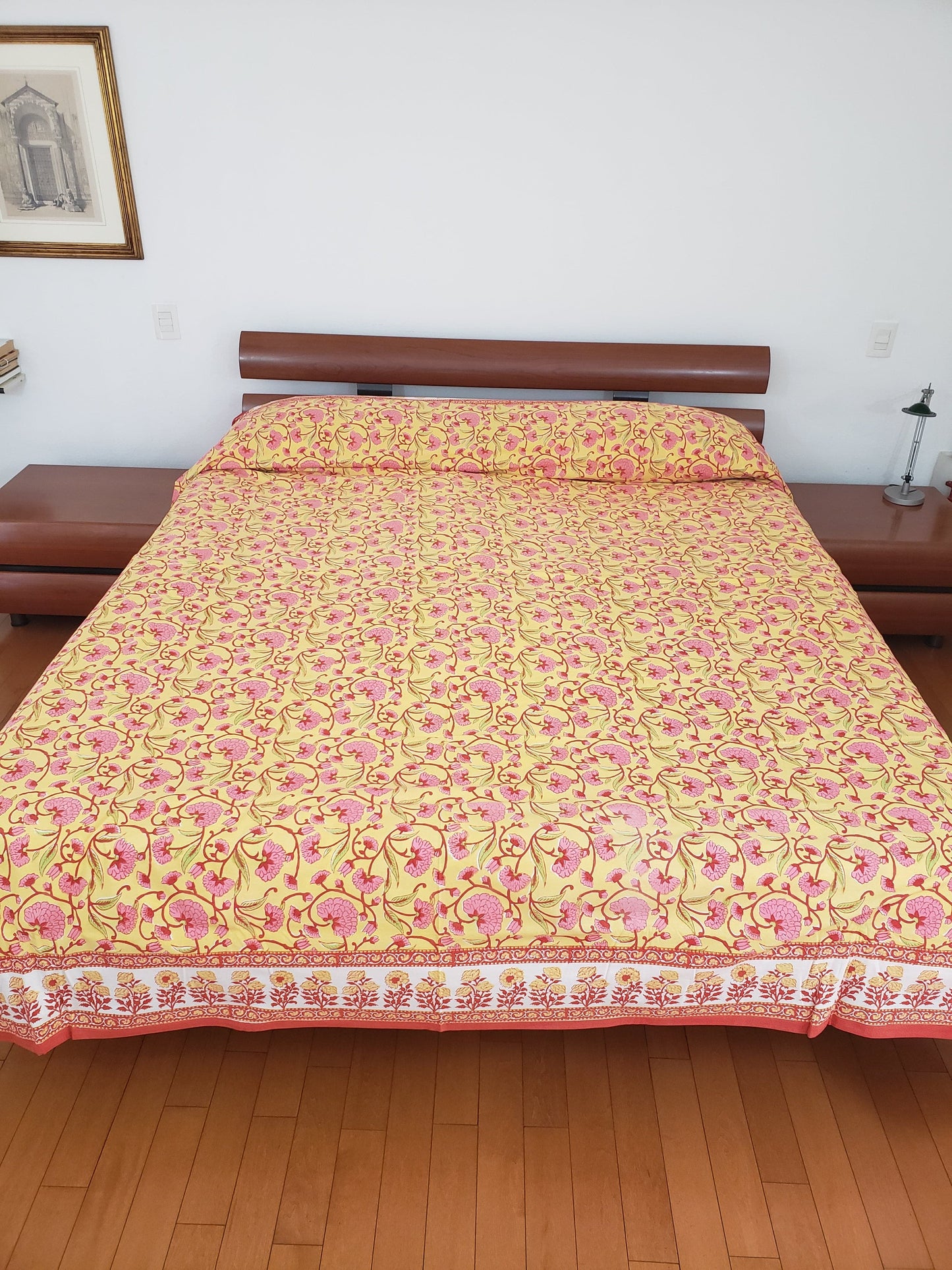 Vista delantera de sobrecama 100% algodón estampado a mano, base color amarilla con flores rosas y tallos rojos. Hecho en la India.