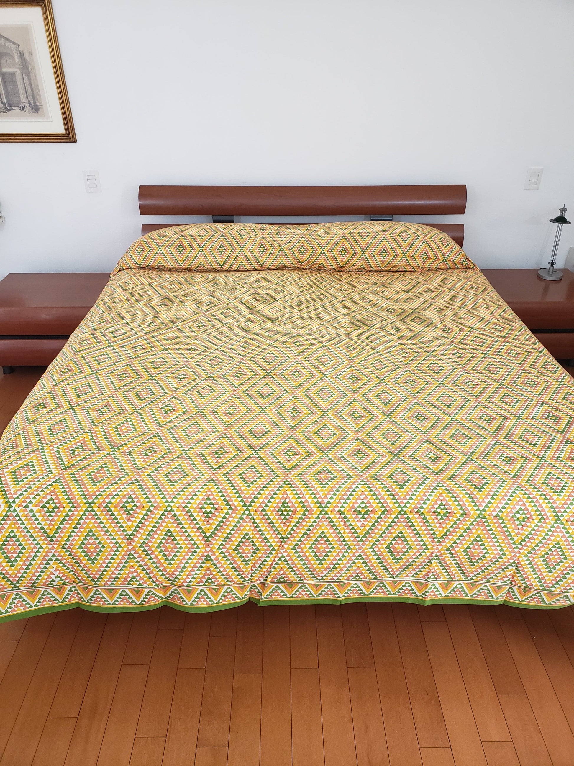 Detalle de sobrecama 100% algodón estampado a mano, con diseño en triángulos color ocre, verde y amarillo. Hecho en la India.