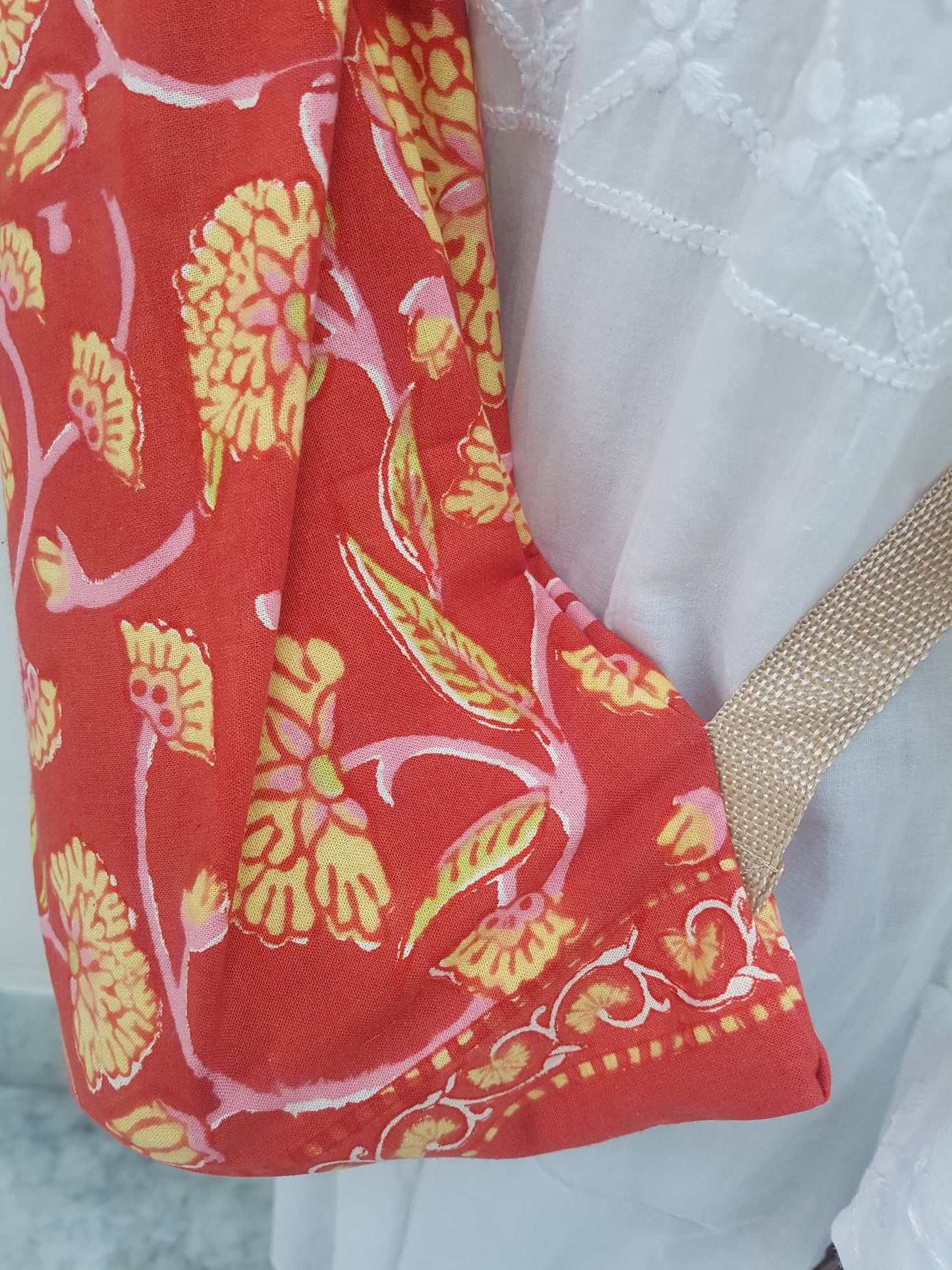 Detalle de correa beige en funda para tapete de yoga 100% algodón, estampada a mano roja con flores amarillas y tallos rosas. Hecha en la India.