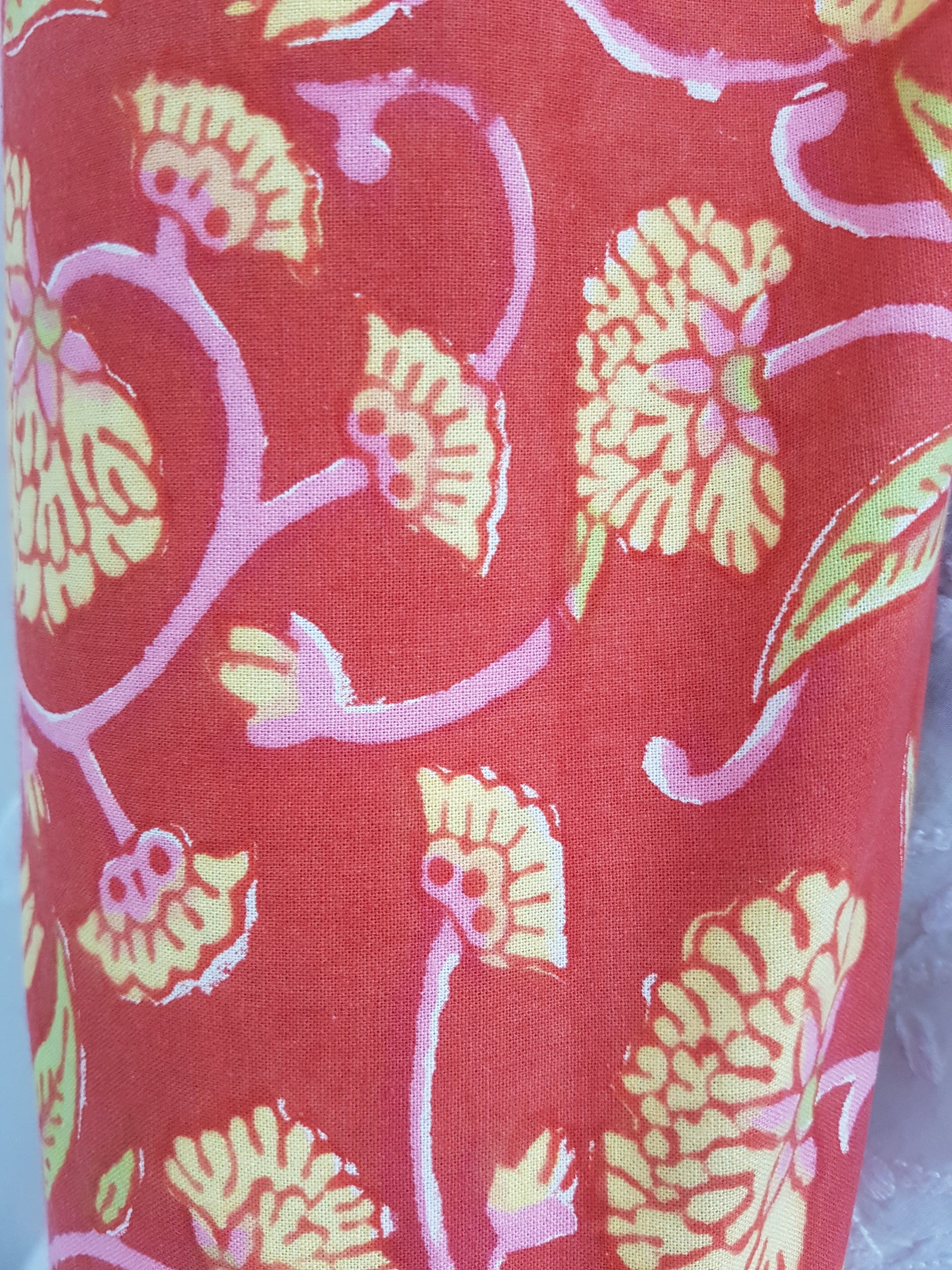Detalle de estampado a mano rojo con flores amarillas y tallos rosas.