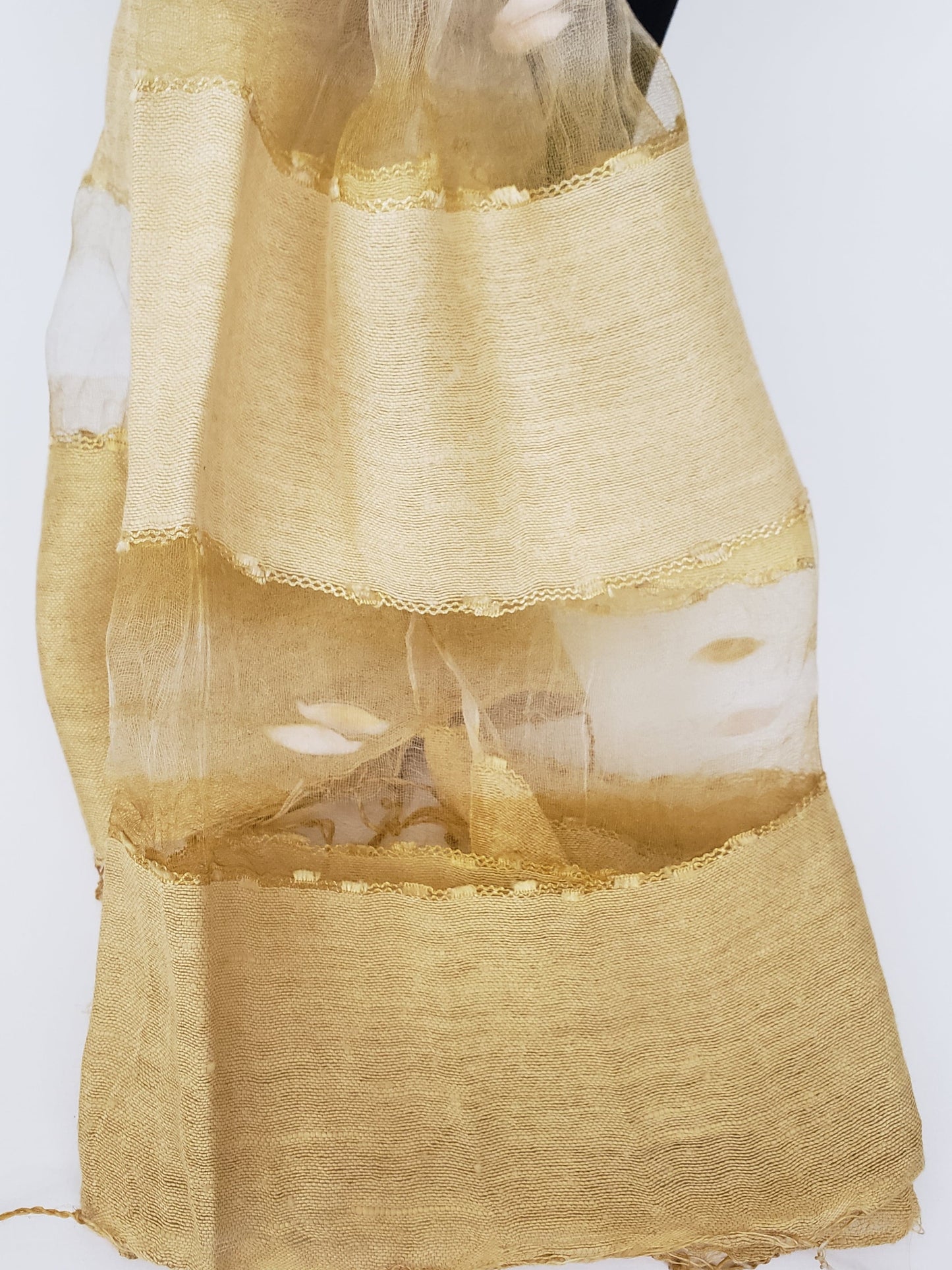 Detalle de mascada de seda cruda en distintos tonos amarillos y dorados con transparencias y seda encapsulada. Hecha en la India.