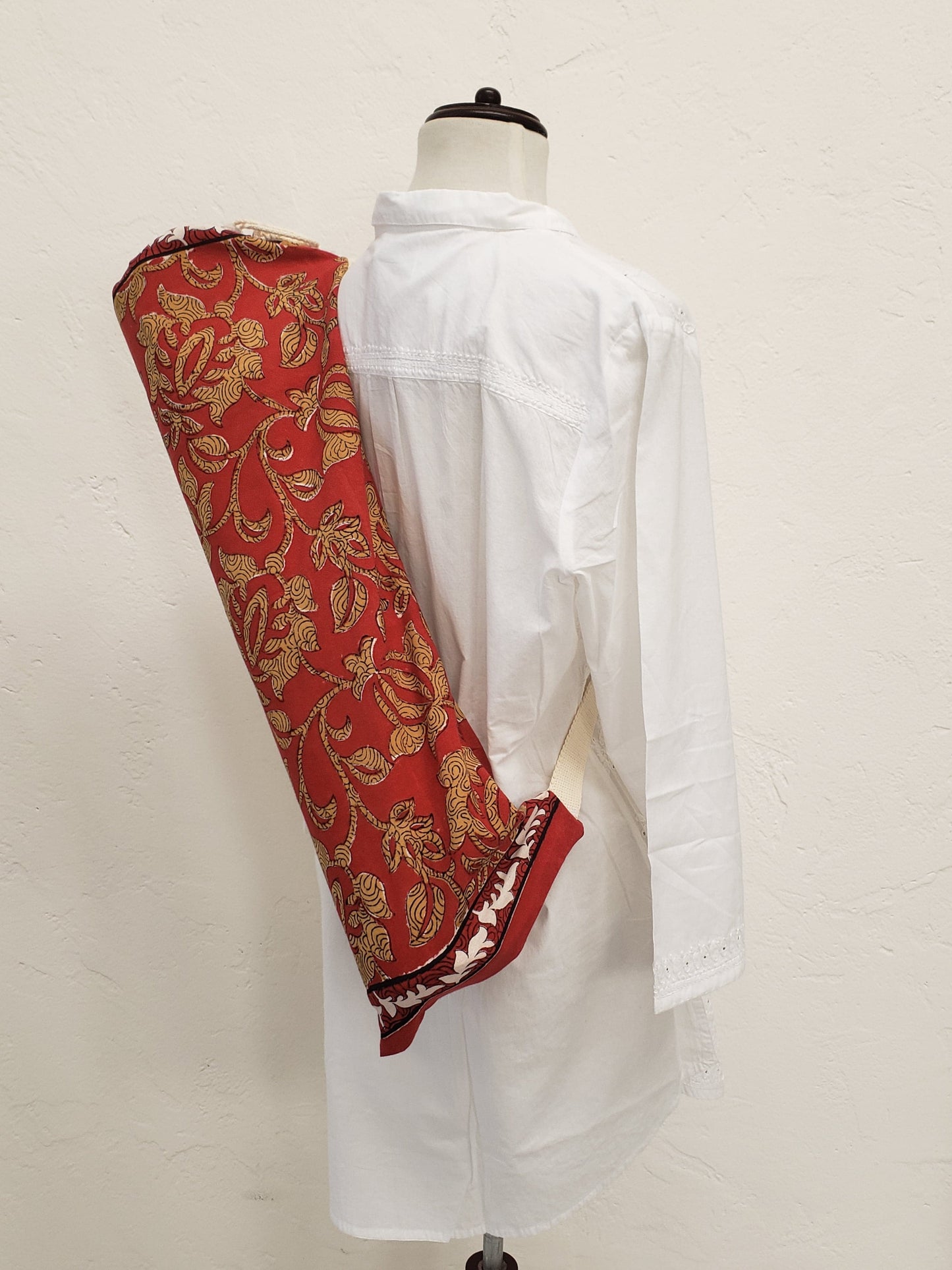Funda para tapete de yoga 100% algodón, color rojo quemado estampada a mano con flores beige con correa en color beige.