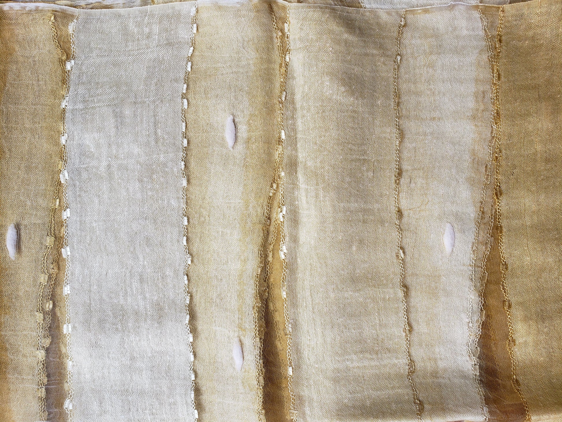Detalle de mascada de seda cruda en distintos tonos amarillos y dorados con transparencias y seda encapsulada. Hecha en la India.