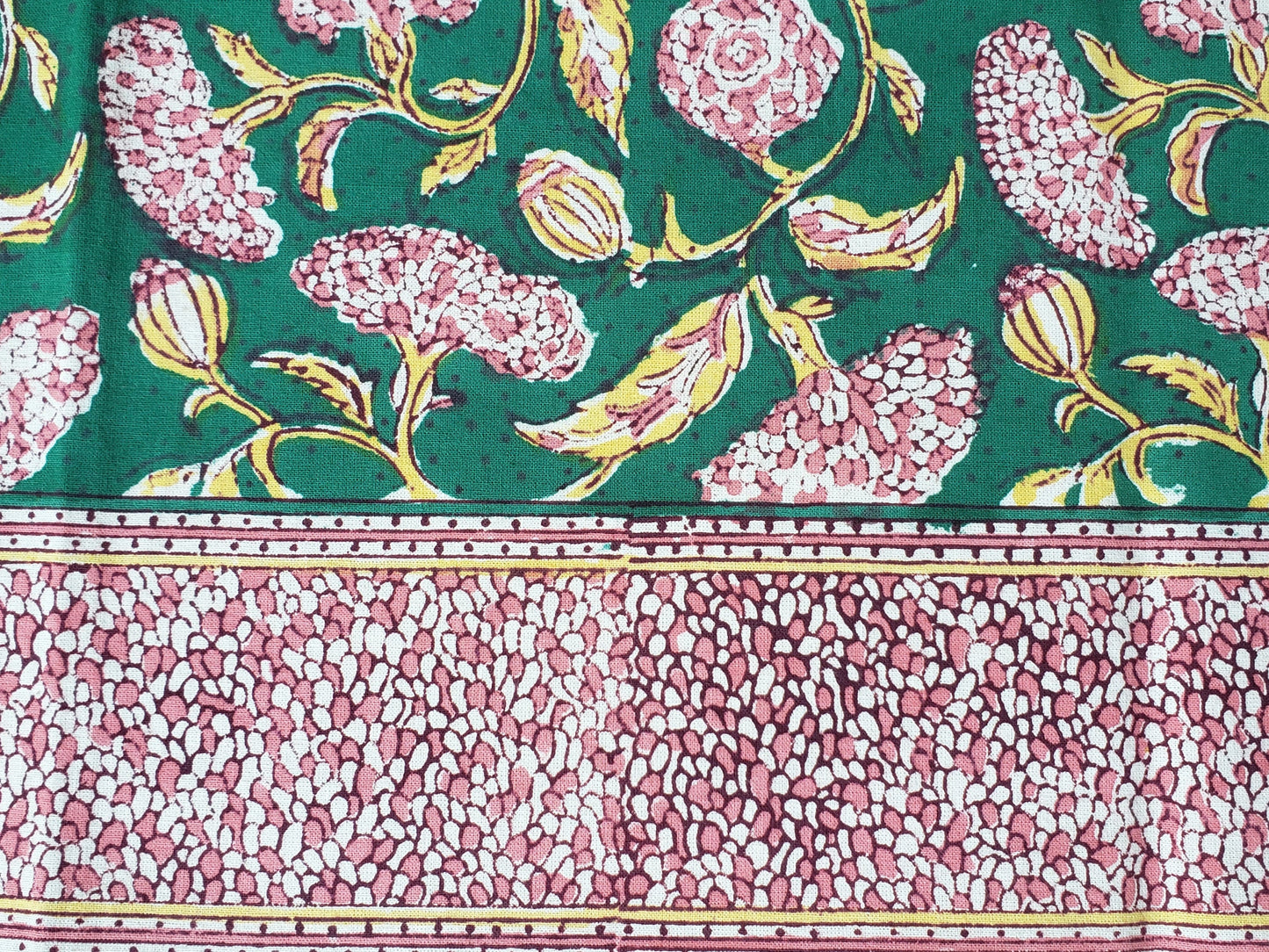 Detalle de borde de sobrecama 100% algodón estampado a mano, base verde obscuro con flores rosas. Hecho en la India.