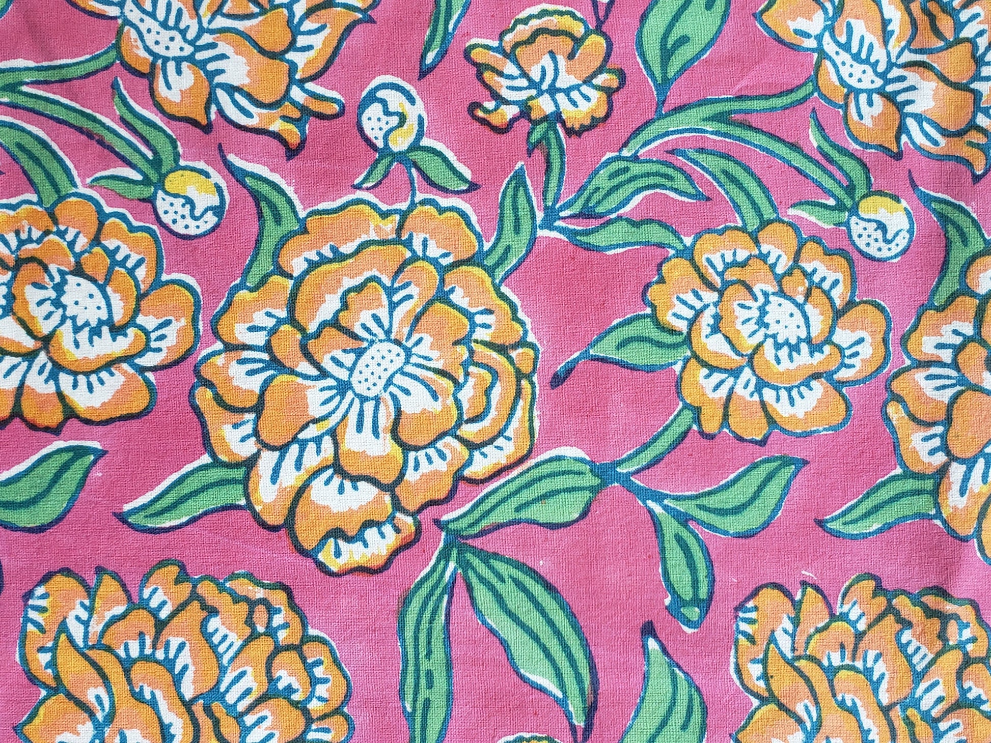 Sobrecama 100% algodón estampado a mano, base rosa con flores naranjas y tallos verdes. Hecho en la India.
