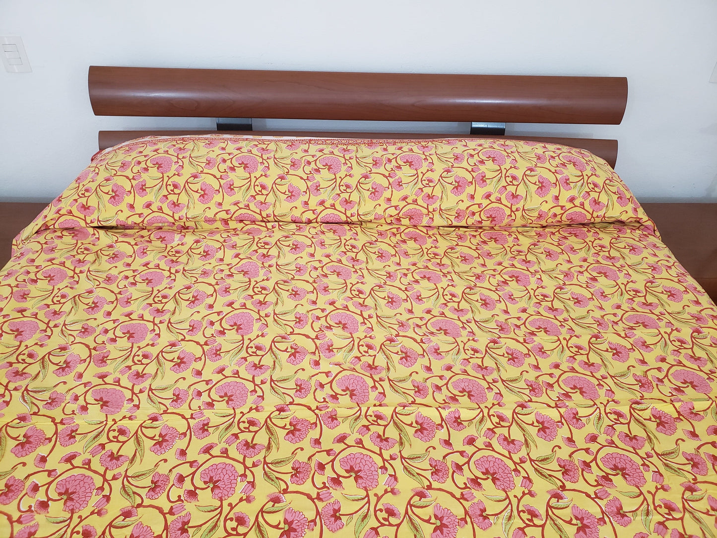 Detalle de sobrecama 100% algodón estampado a mano, base color amarilla con flores rosas y tallos rojos. Hecho en la India.